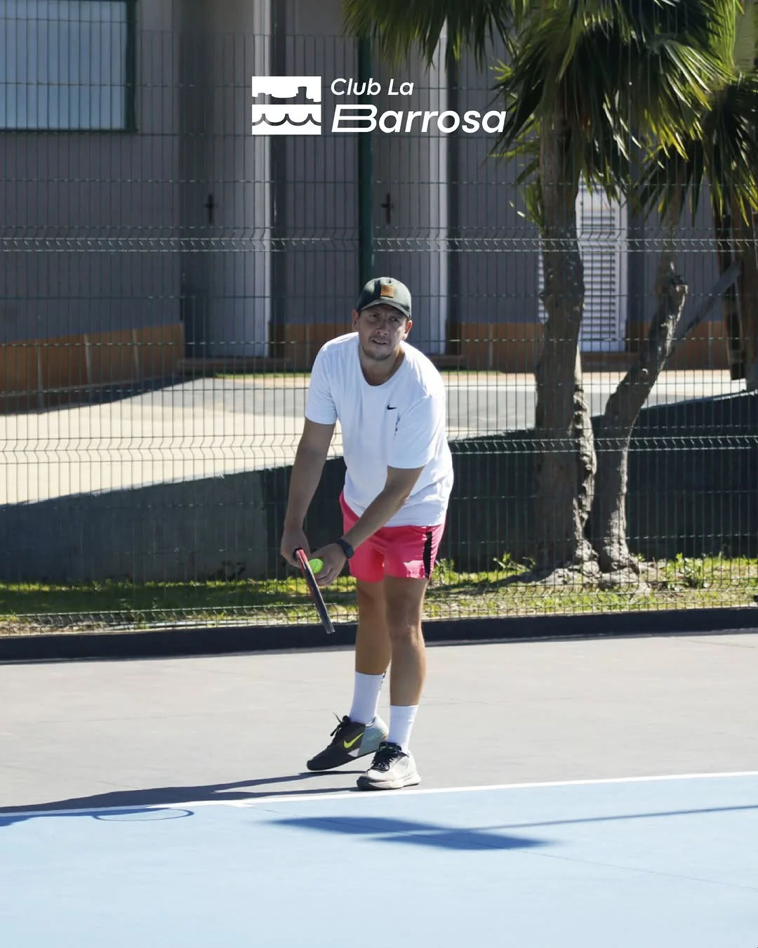 Jugador preparando el saque en la pista de tenis