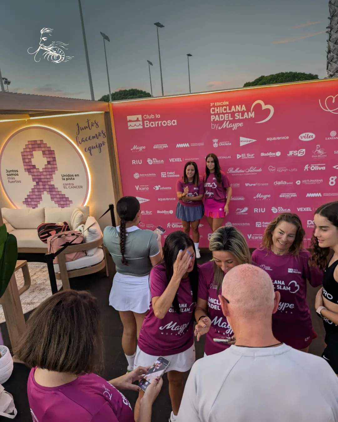 Jugadoras del torneo en el photocall del Club La Barrosa junto a la zona de descanso con el lazo contra el cáncer